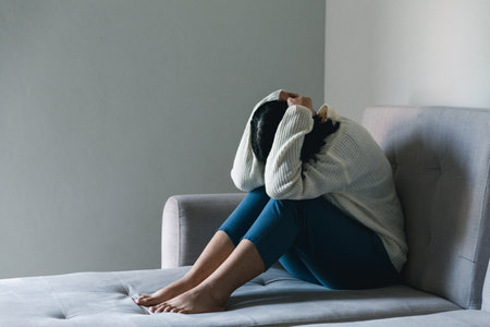 Concept of sad teenage girl depression. Upset teenage girl sitting at window indoors. Anxiety young woman Despair and stress. Lonely and unhappy female are social victims. loneliness youth in home.の写真素材