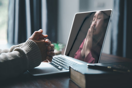 Christian online technology concept. Hands praying of christian with digital computer laptop, Online live church for sunday service. Asian catholic woman are reading Holy bible book and online study.の写真素材