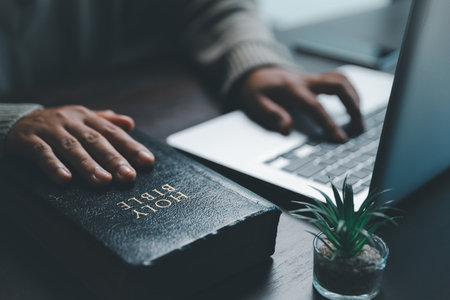 Christian online technology concept. Hands praying of christian with digital computer laptop, Online live church for sunday service. Asian catholic woman are reading Holy bible book and online study.の写真素材