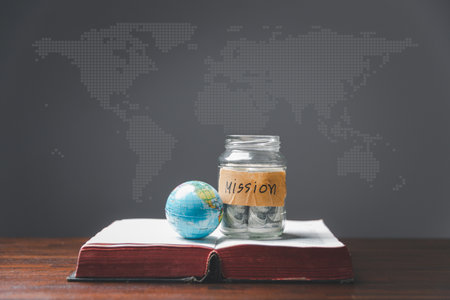 Savings jars full of money and globe with Holy Bible for mission, Mission christian idea. bible and book on wooden table, Christian background for great commission or earth day concept.の写真素材