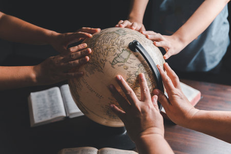 Christian group praying for globe and people around the world on wooden table with bible. Christian small group praying together around a wooden table with bible page in homeroom.の写真素材