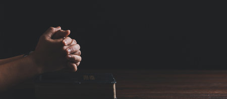 Hands folded in prayer on a Holy Bible in church concept for faith. banner with copy spaceの写真素材