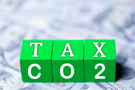 Green wooden cubes with CO2 TAX word on US dollars background. Concept of green Co2 Tax. Carbon tax, environmental and social responsibility business concept. Taxation for nature pollution.の写真素材