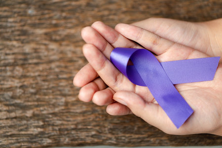 Purple ribbon for the awareness about the unacceptability of the violence against women on dark gray rustic wooden surface. Top view with space for text. Domestic violence awareness.の写真素材