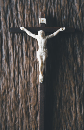 Wooden Christian cross crucifix on a grunge board background. Wooden Christian cross on grey table against blurred lights, space for text.の写真素材