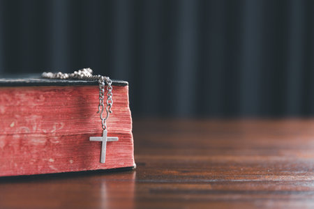 Christian cross crucifix with holy bible background. Wooden Christian cross on grey table against...