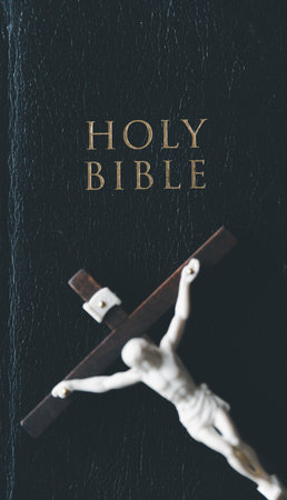 Wooden Christian cross crucifix on holy bible background. Wooden Christian cross on grey table against blurred lights, space for text.の写真素材
