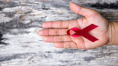 A beautiful red ribbon is on hand is the symbol of aid, support and campaign.A hand is holding a red ribbon. Ribbons have many differences colours such as blue, white, pink red orange white and purpleの写真素材