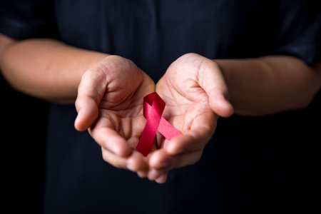 A beautiful red ribbon is on hand is the symbol of aid, support and campaign.A hand is holding a red ribbon. Ribbons have many differences colours such as blue, white, pink red orange white and purpleの写真素材