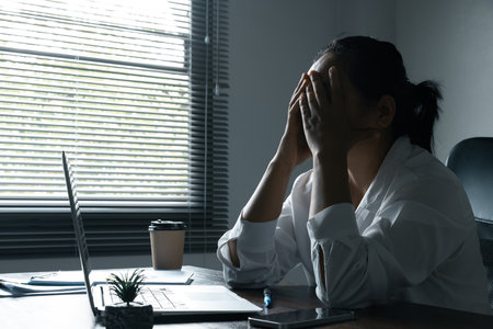A woman battles depression and stress in her workplace, highlighting the challenges faced by professionals. This image captures the impact of mental health on employees in a corporate environment.の写真素材