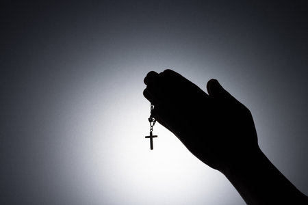Praying hands holding a rosary, Close up holding necklace with cross, pray for god in the dark,...