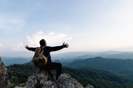 Male tourist on top of rocky mountain. A peaceful man meditating yoga relaxing alone sitting on a...