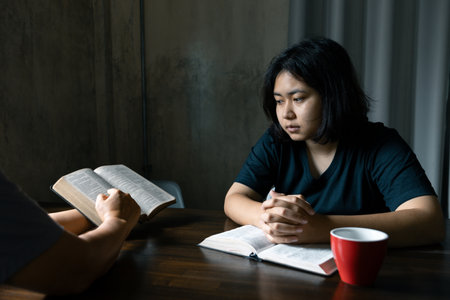Christian family praying together concept. Child and mother worship God in home. Woman and boy hands praying to god with the bible begging for forgiveness and believe in goodness.の写真素材