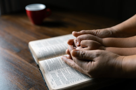 Christian family praying together concept. Child and mother worship God in home. Woman and boy hands praying to god with the bible begging for forgiveness and believe in goodness.の写真素材