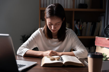 Christian online technology concept. Hands praying of christian with digital computer laptop, Online live church for sunday service. Asian catholic man are reading Holy bible book and online study.の写真素材