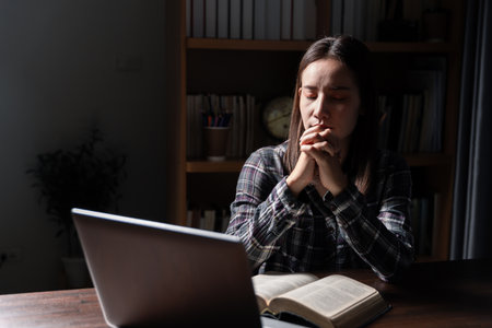 Christian online technology concept. Hands praying of christian with digital computer laptop, Online live church for sunday service. Asian catholic man are reading Holy bible book and online study.の写真素材