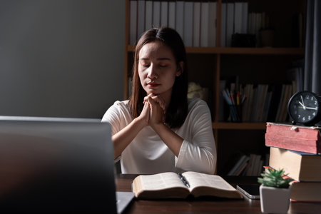 Christian online technology concept. Hands praying of christian with digital computer laptop, Online live church for sunday service. Asian catholic man are reading Holy bible book and online study.の写真素材