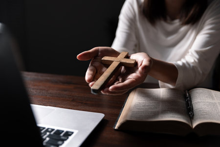Christian online technology concept. Hands praying of christian with digital computer laptop, Online live church for sunday service. Asian catholic man are reading Holy bible book and online study.の写真素材
