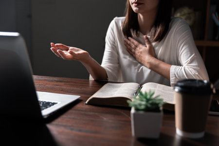 Christian online technology concept. Hands praying of christian with digital computer laptop, Online live church for sunday service. Asian catholic man are reading Holy bible book and online study.の写真素材