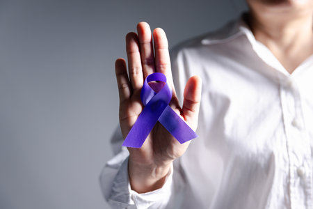 Woman with purple ribbon on palm background, closeup with space for text. Domestic violence awareness. Purple Ribbon for supporting people living. Healthcare and World cancer day concept.の写真素材