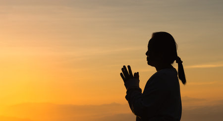 Woman raising his hands in worship. Christian Religion concept. Silhouette woman on sunrise background. Christian female prayers to God in faith. Women raise hands in praise with faith and peace.の写真素材