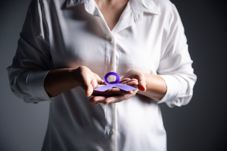 Woman with purple ribbon on grey background, closeup with space for text. Domestic violence awareness. Purple Ribbon for supporting people living. Healthcare and World cancer day concept.の写真素材
