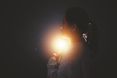 Hands folded in prayer in church. Concept for faith, spirituality and religion. Woman praying in the morning have Yellow lights and sparkles coming. Christian life crisis prayer to god.の写真素材