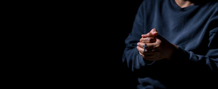 Woman person hand with jesus christ cross praying in dark background. Female christian worship to god in faith. Girl christian meditation and pray in christ. Christianity religion concept.の写真素材