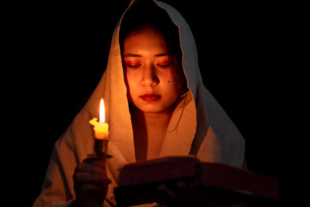 Candle light with young girl praying in dark night background. Woman person worship God with faith and belief. religion, christian prayer concept. Christian teenage girl and faith.の写真素材