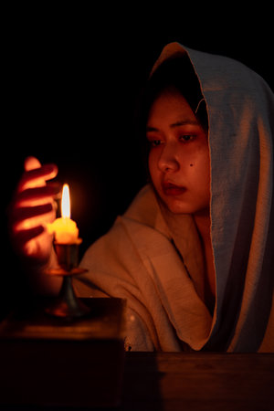 Candle light with young girl praying in dark night background. Woman person worship God with faith and belief. religion, christian prayer concept. Christian teenage girl and faith.の写真素材