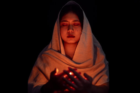 Young girl with candle light praying in dark night background. Woman person worship God with faith and belief. religion, christian prayer concept. Christian teenage girl and faith.の写真素材
