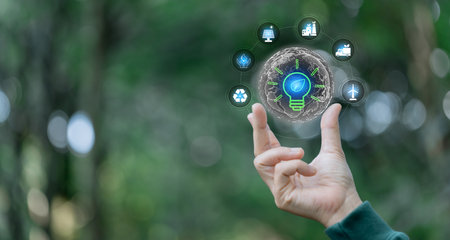 Hand holding light bulb against nature with eco environment icon, Save world, technology sustainable alternative environment concept. Energy of natural gas sustainable, business on green background.の写真素材