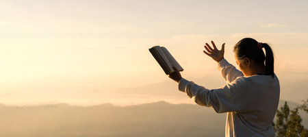 Silhouette of prayer woman worship to God with bible in morning on sunrise sky background. Person hands open palm up worship. God helping catholic easter lent mind pray. Christian religion concept.の写真素材