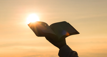 Silhouette of prayer woman worship to God with bible in morning on sunrise sky background. Person hands open palm up worship. God helping catholic easter lent mind pray. Christian religion concept.の写真素材
