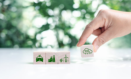 Hand put wooden cubes with green net zero icon and green icon on bokeh nature. Net zero and carbon neutral concept. Net zero greenhouse gas emissions target. Climate neutral long term strategy.の写真素材