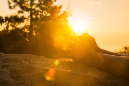 Silhouette of woman hands praying for worship God at sunrise sky background. Christians pray to jesus christ for calmness. In morning people got to a quiet place and prayed. Kneel to pray at mountainの写真素材