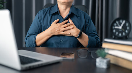 Businesswoman praying at work. Contemplative prayer thinking in office. Hands folded in prayer gesture beg about something. woman with hands clasped praying while sitting at desk in office.の写真素材