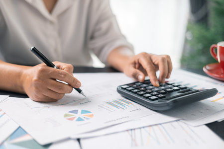 Businesswoman working on desk office with using a calculator to calculate the numbers, finance accounting concept. Woman accountant use calculator and computer. tax, accounting, statisticsの写真素材