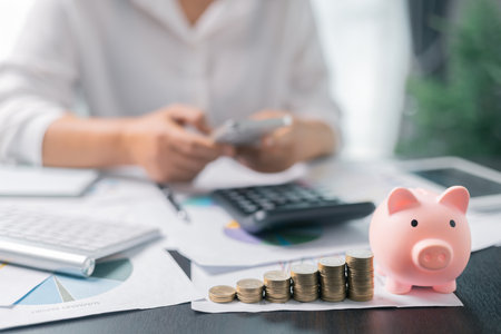 Piggy bank with business stuff, business and finance concept. Business diagram on financial report with coins. Investment results to report to his boss at the meeting.の写真素材