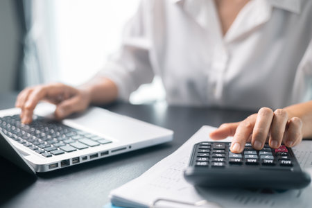 Businesswoman working on desk office with using a calculator to calculate the numbers, finance accounting concept. Woman accountant use calculator and computer. tax, accounting, statisticsの写真素材