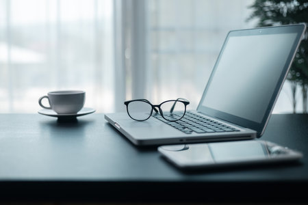 Office workplace with laptop and smart phone on wood table. Workspace, desktop computer, office supplies, houseplant and books at office. desk work concept. laptop Comfortable work table in office.の写真素材