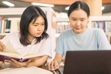 Two young woman, a dedicated student, navigates university life with her friend, embracing education and growth as they pursue their goals together. female student in collegeの写真素材
