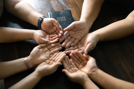 Woman gathered with her Christian friends in church, Bible close as they joined in prayer, feeling warmth of their religious family bond within group.の写真素材