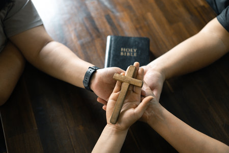 Group of Christian believers clasped hands in prayer, In the church, expressing their faith through worship and reverence for God, symbolized by the cross. Group christian pray concept.の写真素材