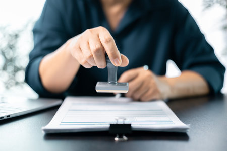 Banking officer stamped the document to approve the loan, finalizing contract and solidifying the finance agreement, fundamental concept in business transactions. approve, loan, stamp, business.の写真素材