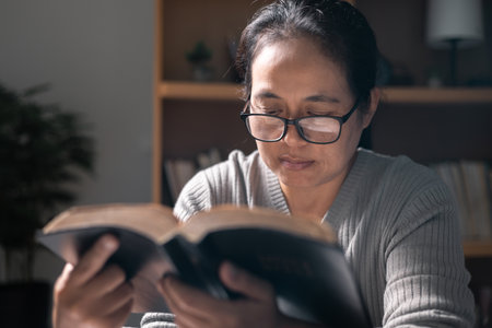 Christian woman spent her evenings reading and studying Bible, deepening her faith and understanding of her religion while taking moments to pray and reflect on what she was learning. bible, book.の写真素材