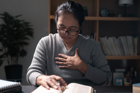 Woman, a person of deep faith, clutched the holy Bible as she knelt in prayer, worshiping with unwavering devotion and embracing the tenets of her Christian religion. bible, prayer, religion, woman.の写真素材
