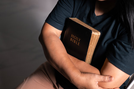 Woman of faith holds the Bible in her hand, believing deeply in the teachings of Jesus Christ and the presence of God, embodying her Christian religion. bible, person, hand, religion, book, faith.の写真素材