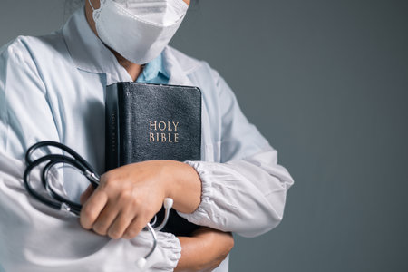 Doctor clasped their hands in prayer, hoping for the best as they provided medical care in hospital clinic. doctor, pray, medicine, health, medical, hand, hospital, care, clinic, hope, prayer, person.の写真素材
