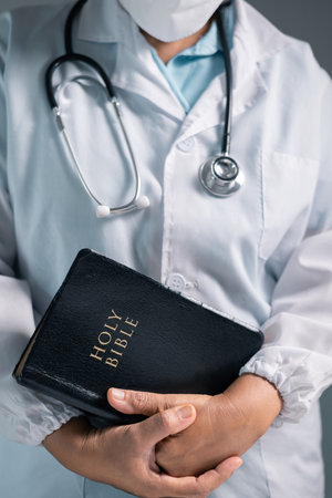 Doctor clasped their hands in prayer, hoping for the best as they provided medical care in hospital clinic. doctor, pray, medicine, health, medical, hand, hospital, care, clinic, hope, prayer, person.の写真素材